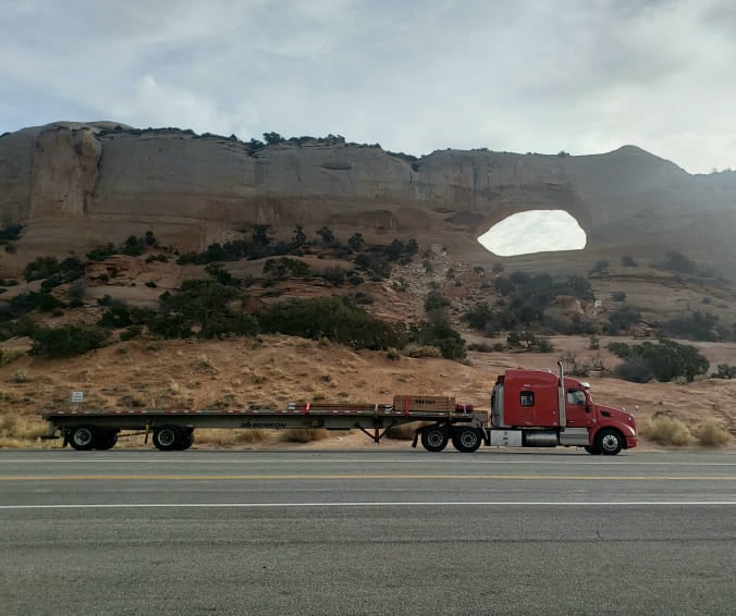 Flatbed truck driving through landscape of the American Southwest